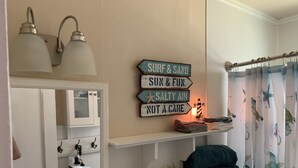 Un bagno con uno specchio, un portasciugamani e uno scaffale con asciugamani e un flamingo decorativo.