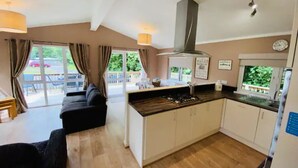 Una cocina moderna con una isla central, un área de comedor con un sofá y ventanas grandes con vistas al exterior.