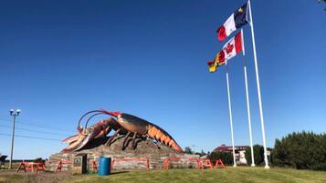 A large lobster sculpture on a grassy field with Canadian flags in the background.