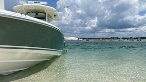 En båt låg förtöjd vid en strand med klart vatten och en mulen himmel.