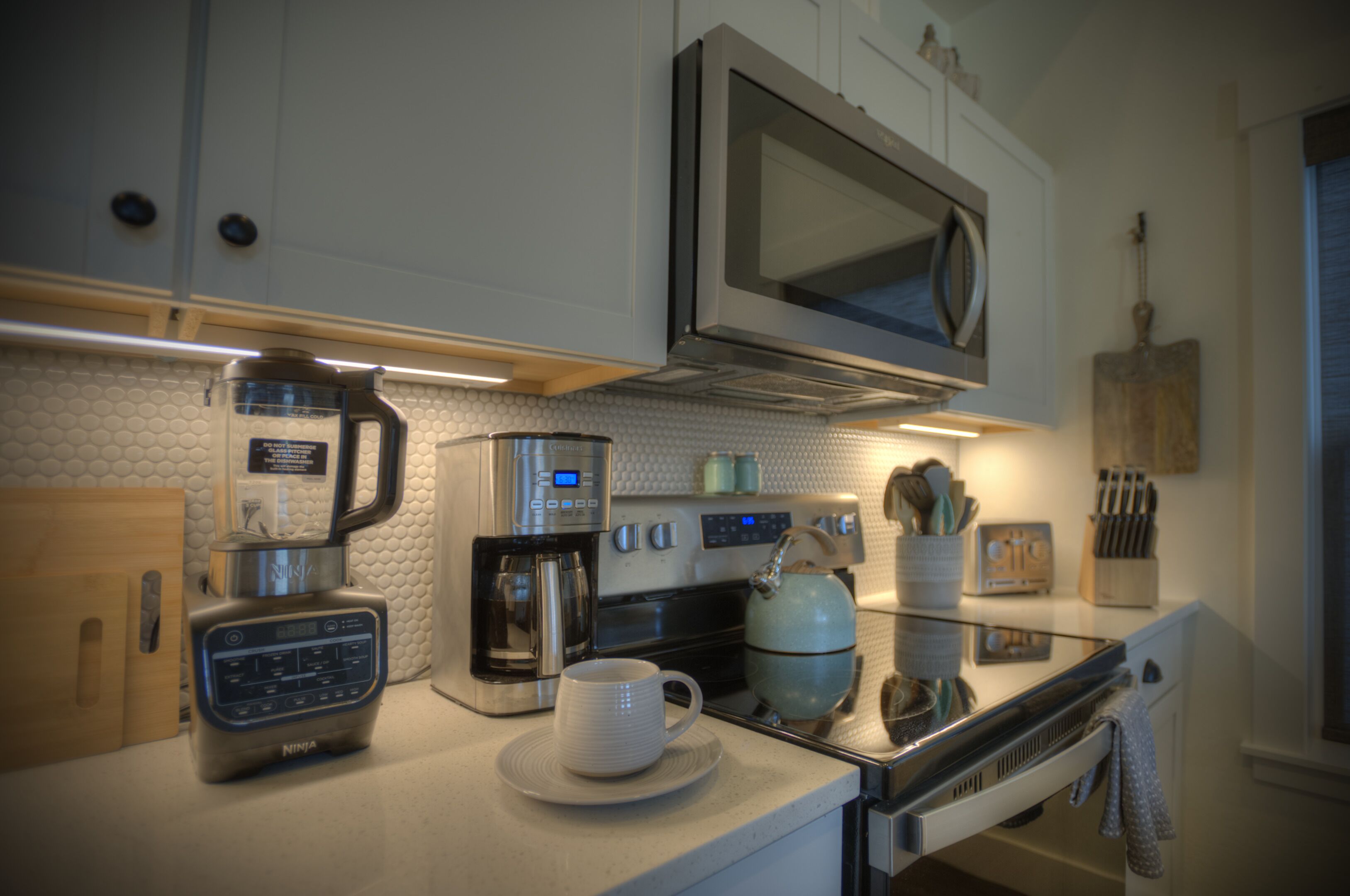 Una cocina moderna equipada con cafetera, microondas, hervidor y cocina de vitrocerámica.