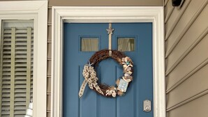 Une porte bleue, ornée d’une guirlande et surmontée d’un paillasson.