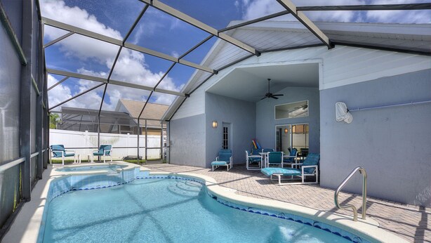 Ein überdachter Pool mit Liegestühlen und einem Deckenventilator.