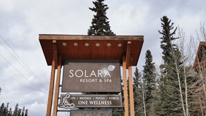 Een houten bord van Solara Resort & Spa met advertenties voor diensten zoals spa, massage en fitness.