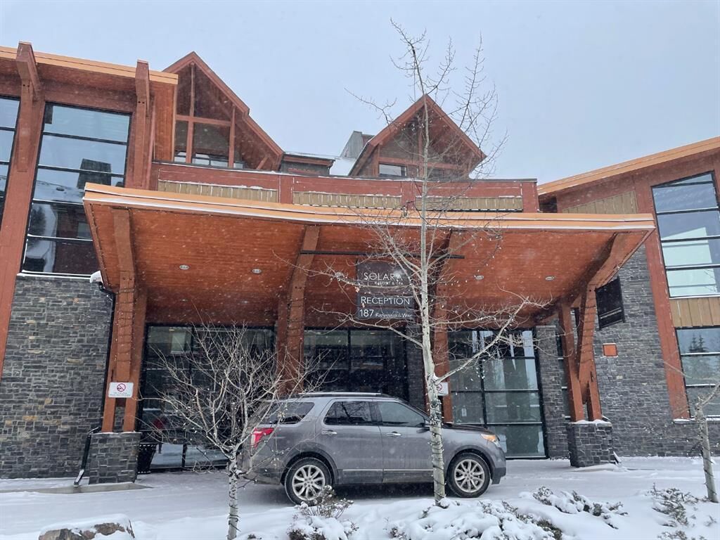 A building with a reception area, a car parked in front, and snow on the ground.