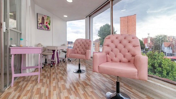 A modern room with large windows, a pink chair, a desk, and a chair with wheels. - Ayenda Eloina (Bogotá)