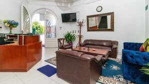 A living room with a brown leather sofa, a blue velvet armchair, a wooden coffee table, and a TV mounted on the wall. - Ayenda Eloina (Bogotá)