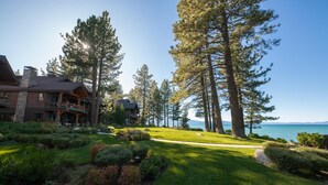 Un gran albergue con un césped cuidado, altos pinos y vista al agua.