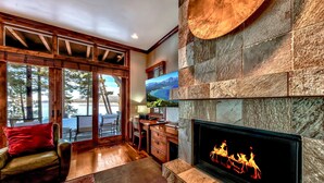 Una sala de estar acogedora con chimenea, muebles de madera y un ventanal con vistas panorámicas.
