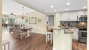 Een ruime keuken met een centraal eiland, houten vloeren en moderne apparatuur.