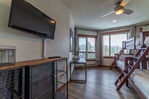Ein Zimmer mit Etagenbetten, einem Fernseher, einem Schreibtisch und einem Fenster mit Blick.