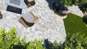 An outdoor patio area with a stone floor, wicker furniture, and a small grassy patch. - Beautiful 4 bedroom 2 bathroom with pool and pool table for your entertainment (Glendale)