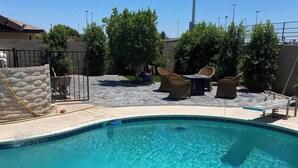 A clear blue swimming pool with a stone wall and a metal gate. - Beautiful 4 bedroom 2 bathroom with pool and pool table for your entertainment (Glendale)