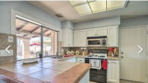 A kitchen with white cabinets, a large island with a sink, a microwave, and an oven. - Beautiful 4 bedroom 2 bathroom with pool and pool table for your entertainment (Glendale)