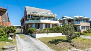 Een tweelaags woonhuis met een overdekt balkon, een zichtbare brievenbus en een verzorgd gazon.