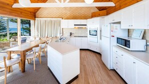 Een moderne keuken met witte kastjes, een centraal eiland en een eetgedeelte met houten stoelen en een tafel.