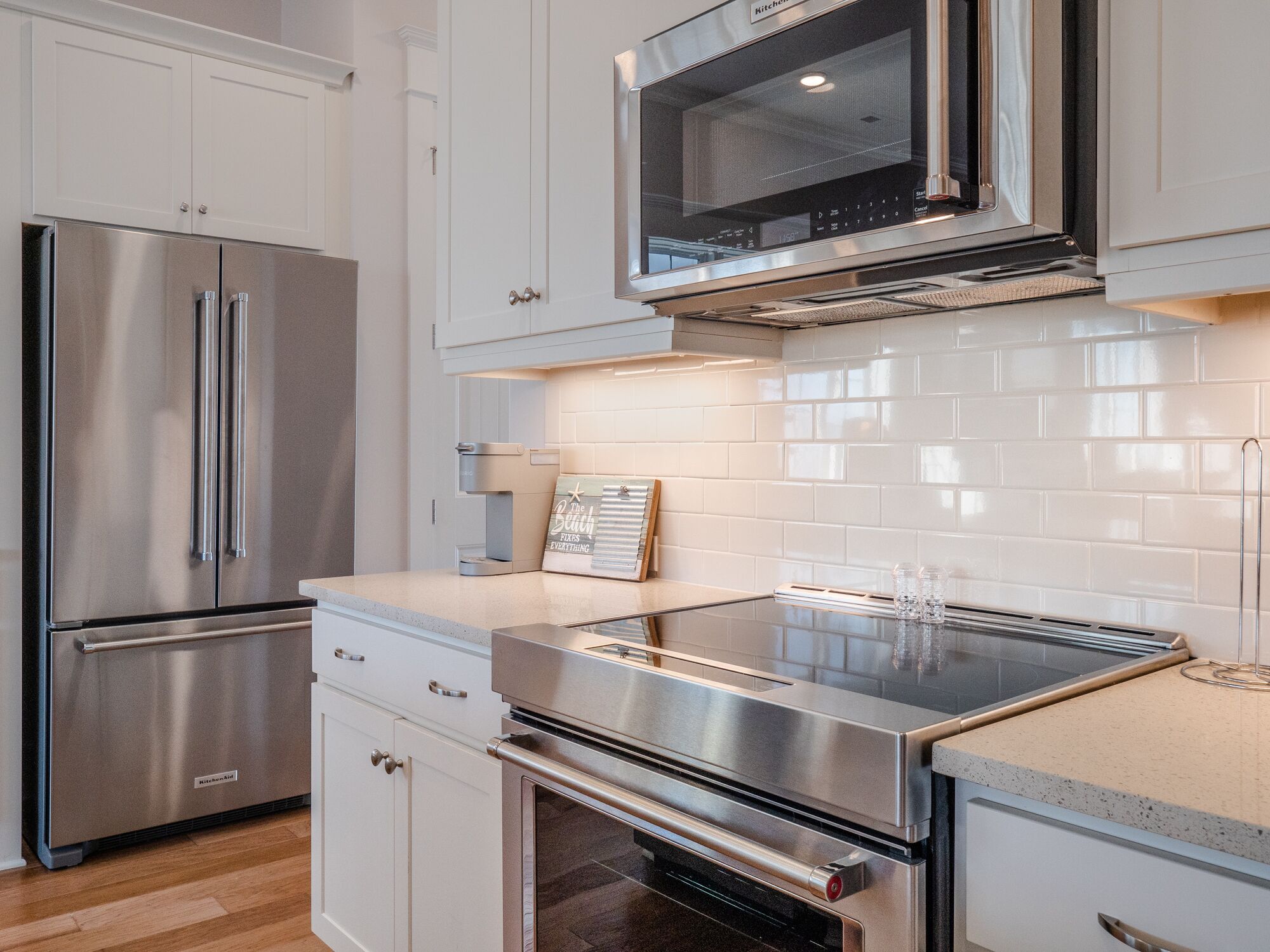 Una cocina moderna con electrodomésticos de acero inoxidable, armarios blancos y salpicadero de azulejos.