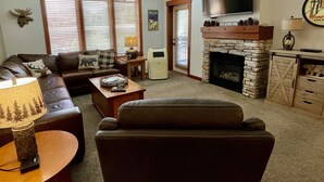 Ein Wohnzimmer mit Kamin, Fernseher und einer Couch.