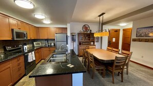 Eine moderne Küche mit Holzschnitzern, einem Edelstahlkühlschrank und einer zentralen Kochinsel mit Spüle.