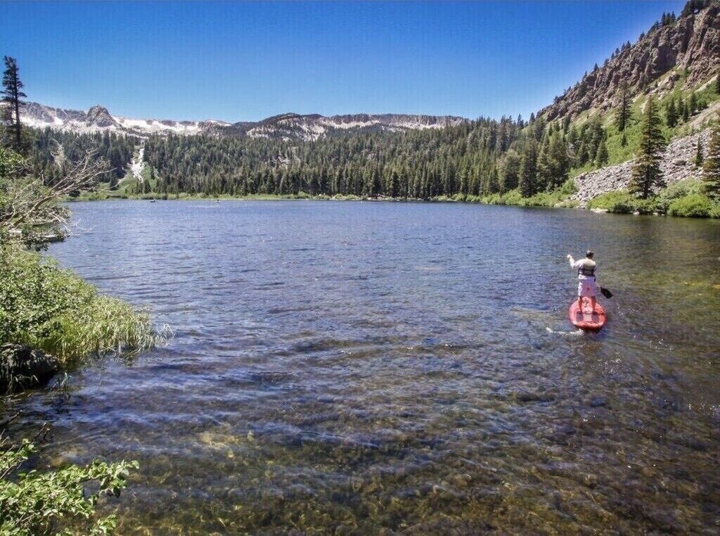 A clear lake surrounded by forested mountains.
