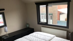 Una camera da letto con un letto, una cassettiera, una finestra e un termosifone.