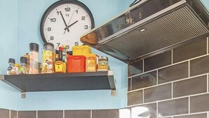 Una cucina con un fornello, un forno e una sveglia appesa al muro.