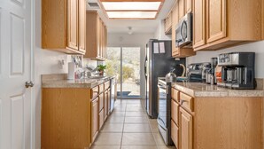 Una cocina con armarios de madera, un refrigerador de acero inoxidable, un microondas, una cafetera y un tostador.