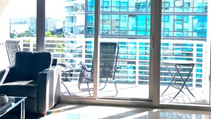 A modern room with a glass door leading to a balcony, a black chair, and a small table.