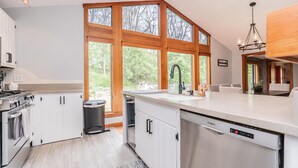 Una cocina moderna con armarios blancos, un lavavajillas Bosch y un amplio ventanal con vistas al exterior.