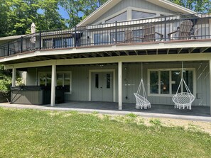 A two-story house with a covered porch, outdoor seating, and a hot tub.