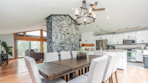 Una cocina amplia con armarios blancos, una isla central y un comedor con una gran mesa de madera y sillas.