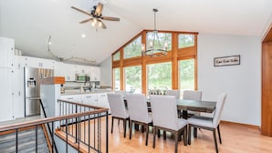 Una cocina amplia con comedor, piso de madera y ventanas grandes.