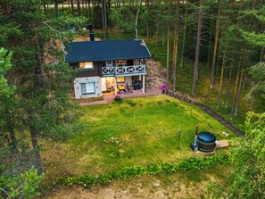 Et tosidet hus med mørkt tag, omgivet af skov.
