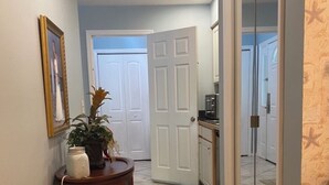 A hallway with a wooden side table, a potted plant, and a framed picture on the wall. - Sea Trail Golf and Beach Get Way (Sunset Beach)