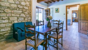 A rustic dining area with a stone wall, wooden furniture, and a tiled floor. - Apartment Olea by Interhome (Guardistallo)