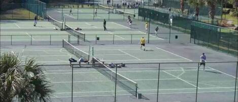 A tennis court with multiple courts, benches, and a fence.