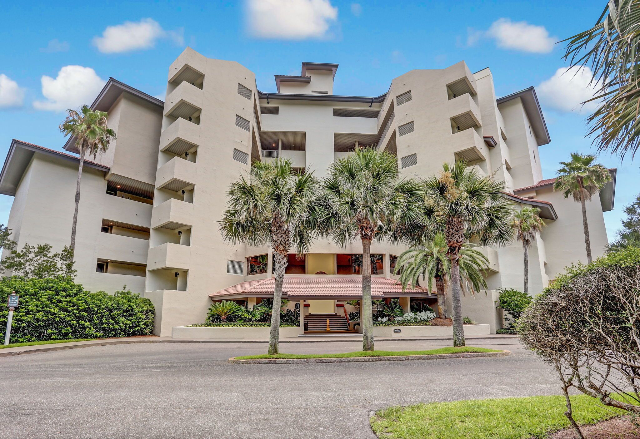 A multi-story hotel with a central courtyard, palm trees, and a red-tiled roof.