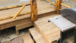 A wooden deck with a grill and benches, a door, and a window. - 8 miles to Mount Rushmore - Sleeps 2 - King Bed (Rapid City)