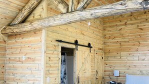 A log cabin room with a bed, a sofa, and a wardrobe. - 8 miles to Mount Rushmore - Sleeps 2 - King Bed (Rapid City)