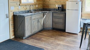 A compact kitchen with wooden walls, a granite countertop, and a refrigerator. - 8 miles to Mount Rushmore - Sleeps 2 - King Bed (Rapid City)