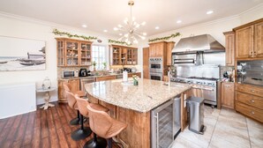 A modern kitchen with granite countertops, stainless steel appliances, wooden cabinets, and a central island with bar stools.