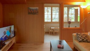 Una sala acogedora con paredes de madera, un televisor, una mesa de centro y un sofá.