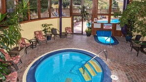Un espace piscine intérieur doté d’un sol en briques, entouré de chaises et de plantes en pot.