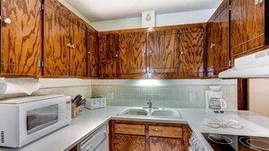 Une cuisine avec des meubles en bois, un four à micro-ondes, une cuisinière et un évier.