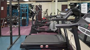 Une salle de sport équipée de tapis de course, d’une machine de musculation et d’un mur recouvert de miroirs.