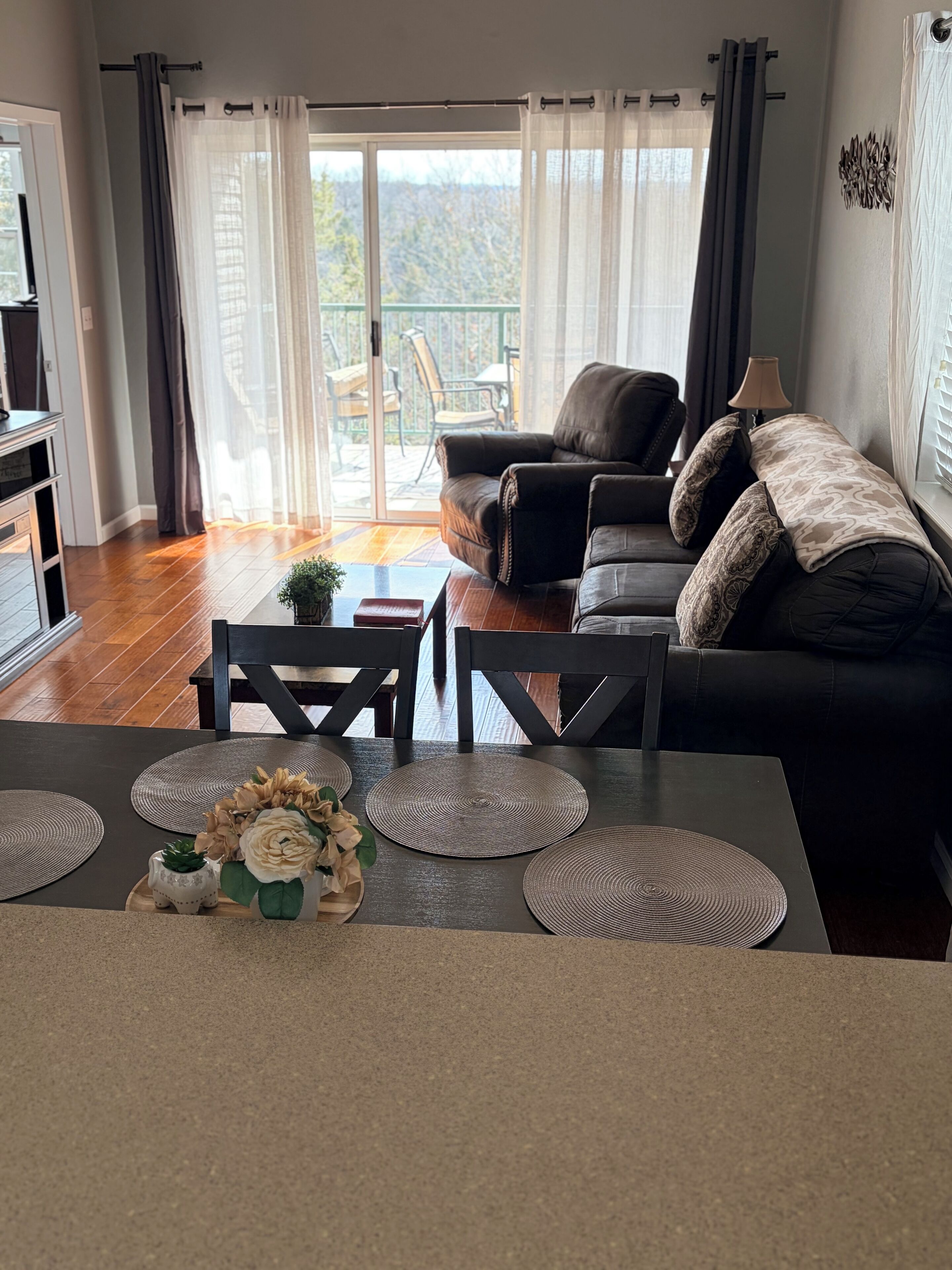 Una sala moderna con sofá, mesa de centro y objetos decorativos. Unos ventanales corredizos dan a un patio exterior.