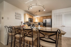 A kitchen with a central island, wooden cabinets, stainless steel appliances, and a chandelier. - Walk to Mountain or Steps to Free Bus Stop/HotTub w/Private Garage-W/D in Unit-Gas Fireplace (Steamboat Springs)