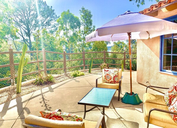 A patio with outdoor furniture, a table, and an umbrella.