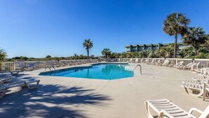 A pool area with lounge chairs and palm trees. - Oceanfront, Top Floor/ Corner Sea Cabin, Gorgeous Views with Pool (Isle of Palms)