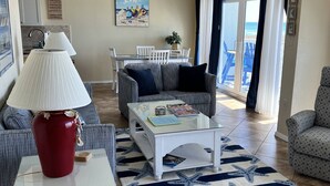 Ein Wohnzimmer mit einer Couch, einem Glastisch, einer roten Vase und einem Teppich mit Seestern-Muster.